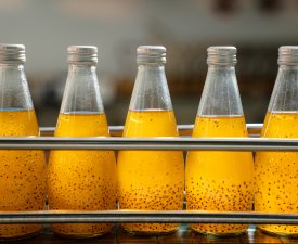 Juice in glass bottles in a factory for the food industry, bottling and transport, Drink factory production line fruit juice beverage product.