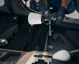 Man clean interior of car service. Chemical washing of carpet textile inside vehicle cabin by worker