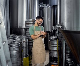 Man working in craft brewery examining production of the beer.